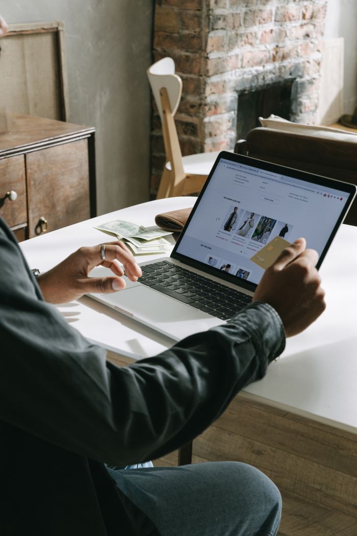who-we-are An adult is using a credit card to shop online on a laptop indoors.